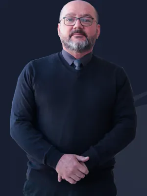 Retrato de Jorge Garcia, contador, de suéter escuro e óculos, em fundo azul-escuro